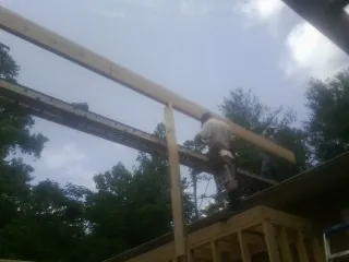 Carpenter setting a ridge beam over a new addition frame — Ice Dam Removal by Roofing Brothers in Fort Ripley