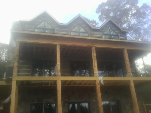 Dormers and porch framing on a large log home under construction — Roof Coating work by our crew in Fort Ripley