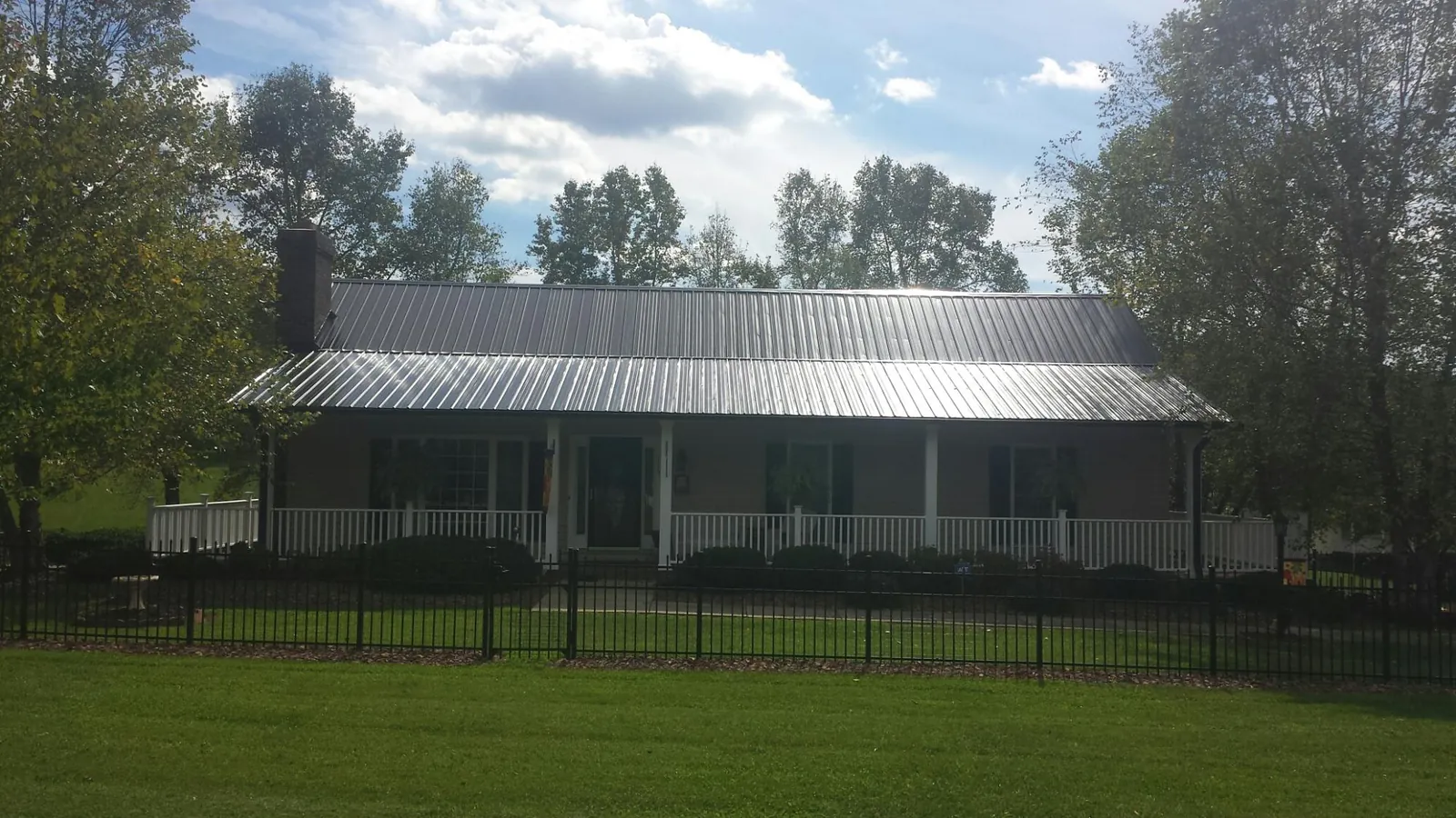 Gray metal roof on a brick ranch with a full width front porch — Gutter Guard Installation work by our crew in Fort Ripley