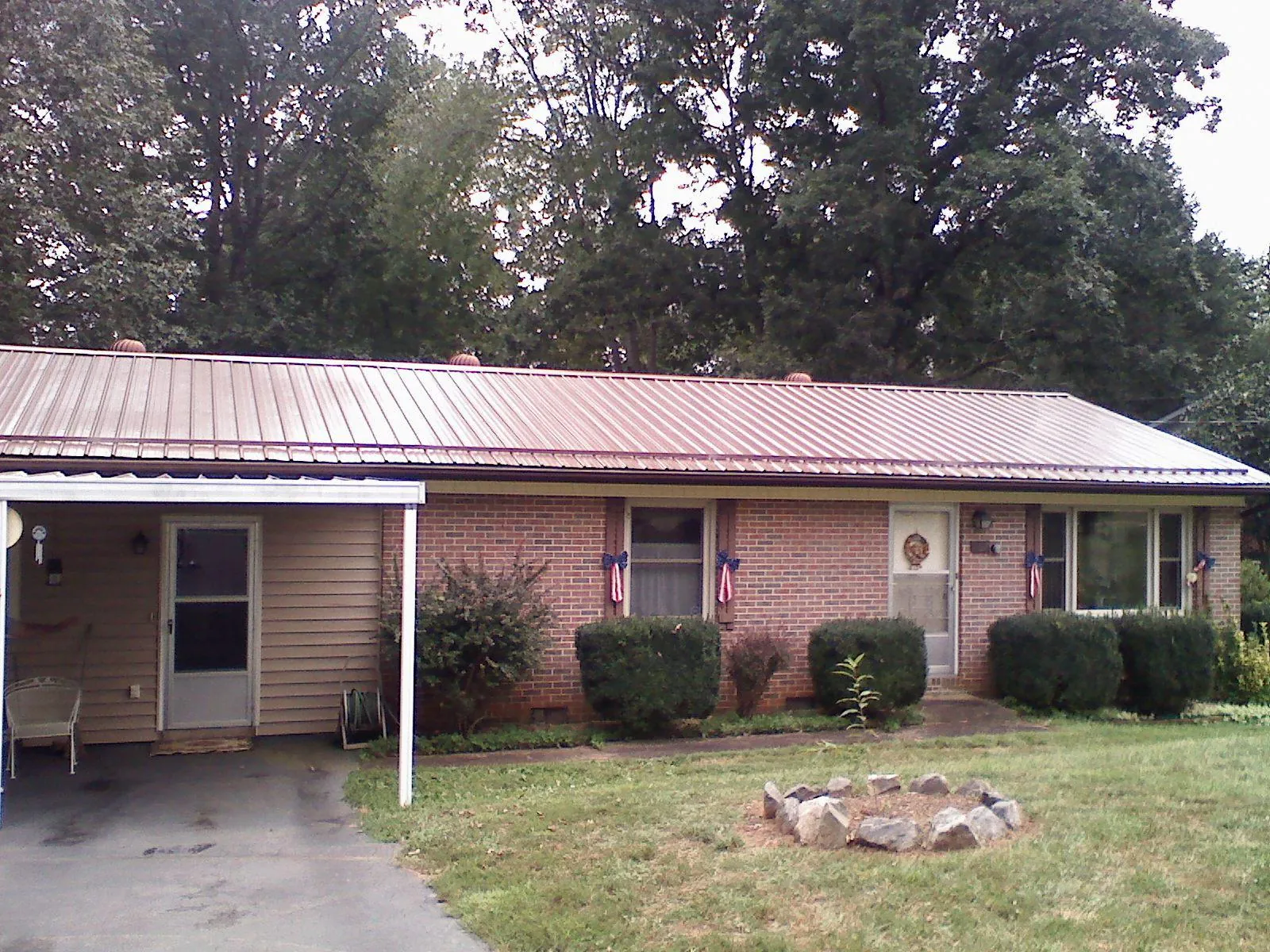 Bronze metal roof and carport on a brick ranch home — Roof Repair work by our crew in Fort Ripley