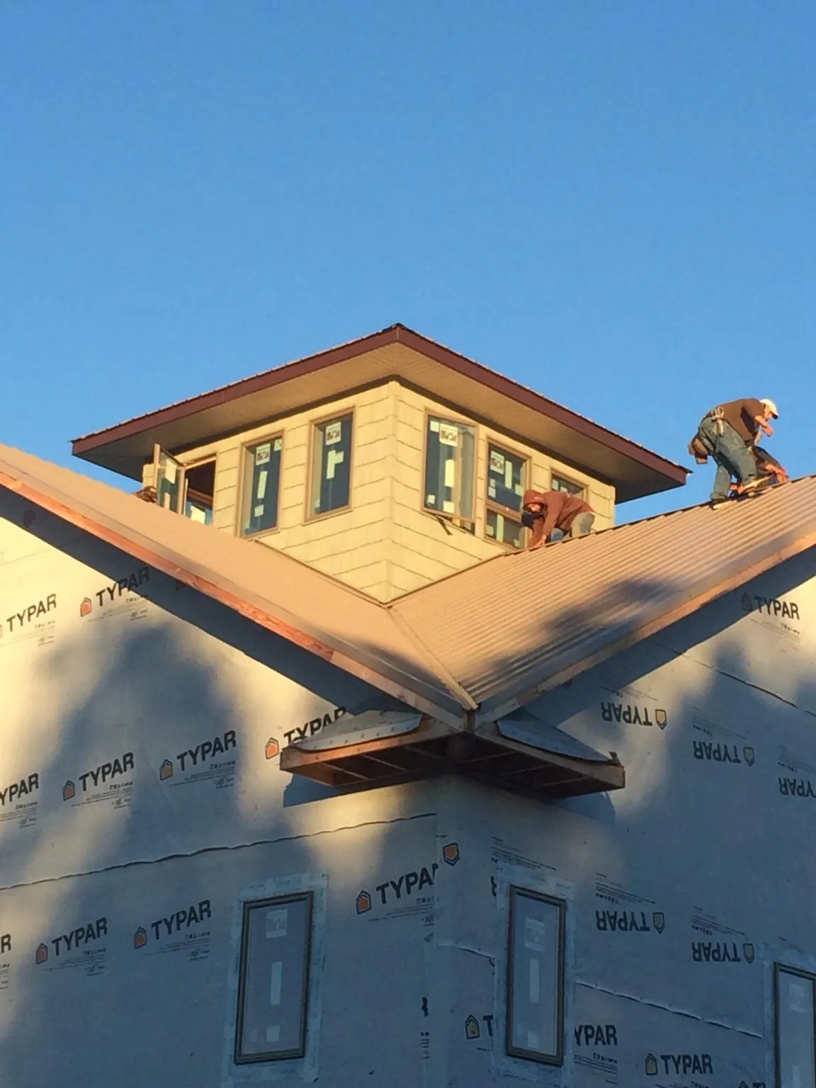 Roofers working around a rooftop cupola on a new metal roof at sunset — Roof Waterproofing in Fort Ripley by Roofing Brothers
